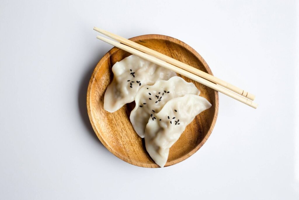Steamed dumplings with sesame on a wooden plate with chopsticks