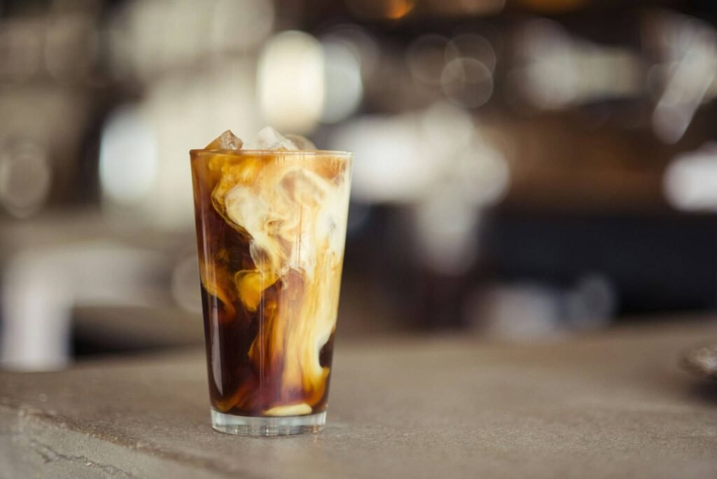 Iced coffee with milk swirling in a tall glass on a cafe counter