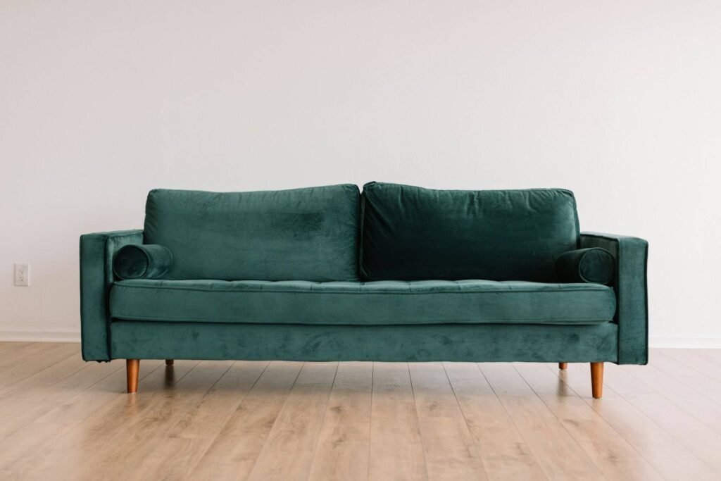 A green velvet sofa against a white wall on an oak floor