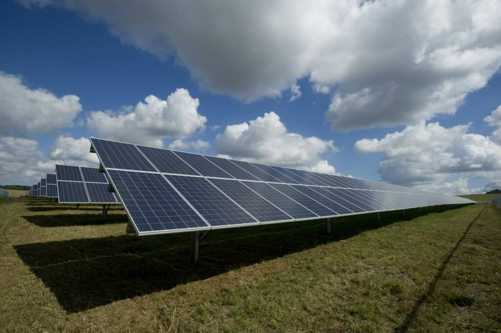 Rows of solar panels in a field under scattered clouds