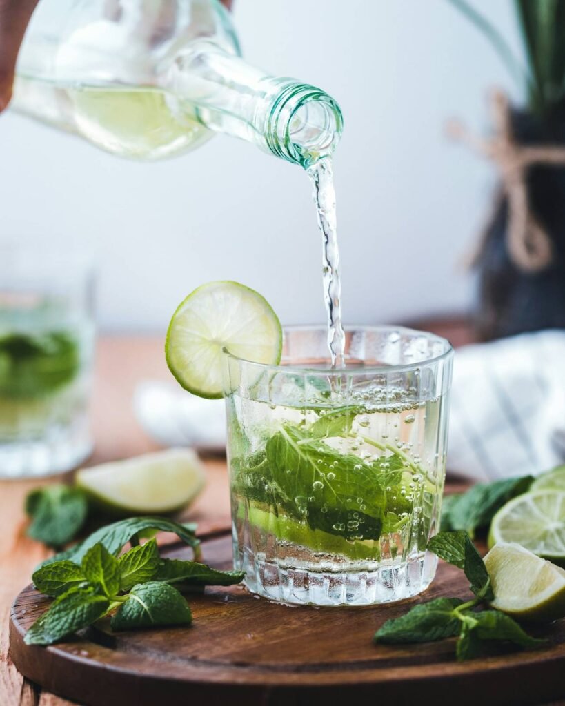 Tonic being poured over lime and mint in a short glass